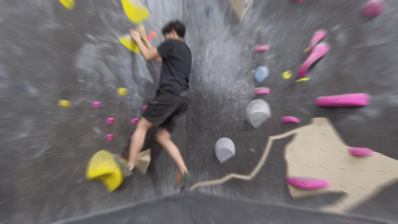 亚洲攀岩者在健身房攀爬室外抱石墙。有趣的室内运动活动。视频素材