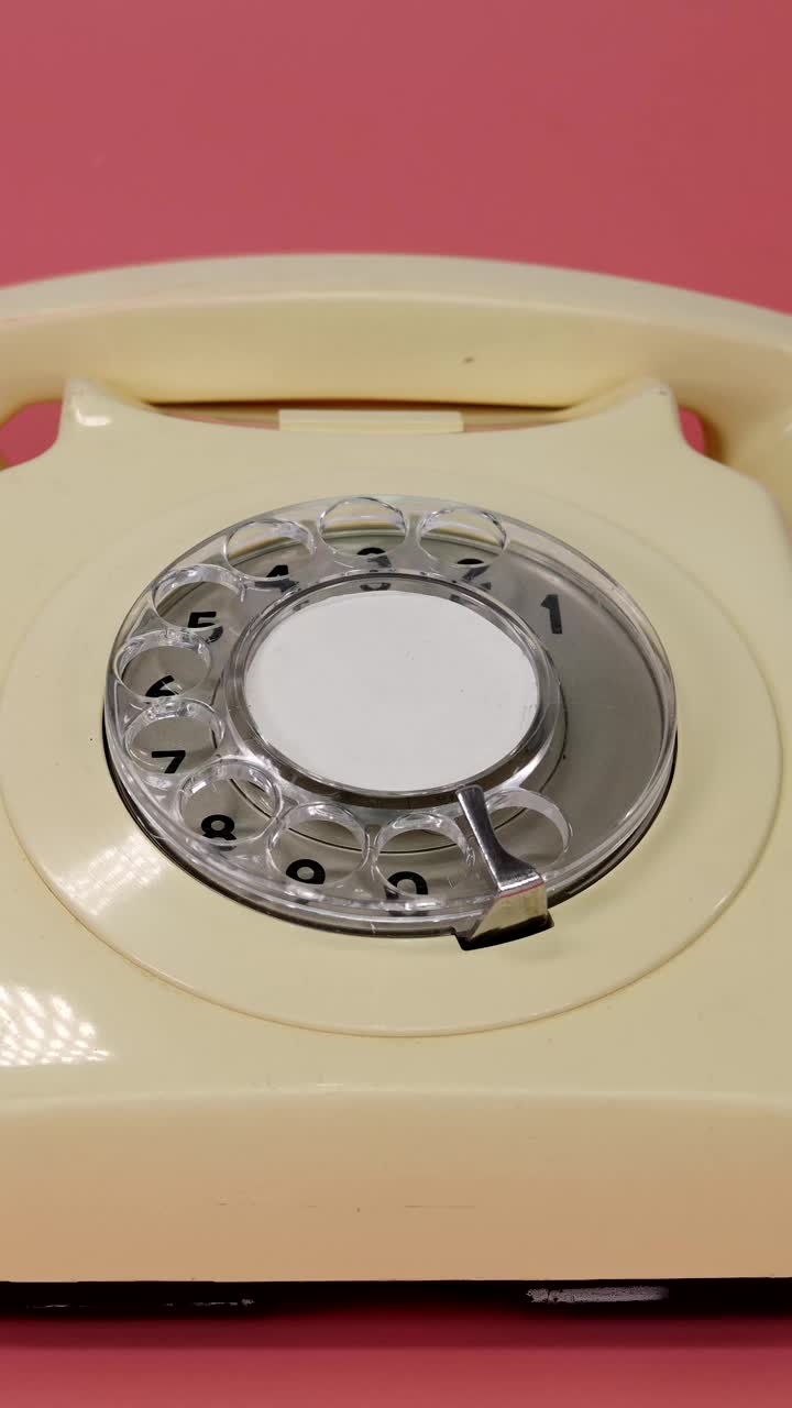 老式复古风格的英国电话的肖像镜头，一个男人的手拿起话筒，又放下话筒，背景是粉红色的视频下载