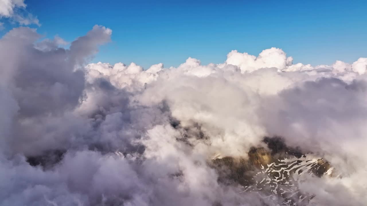 白天在云层垂直发展的山脉上空飞行。云中鸟瞰图，无人机拍摄的地平线稳定图像。时间流逝。天气视频背景视频下载