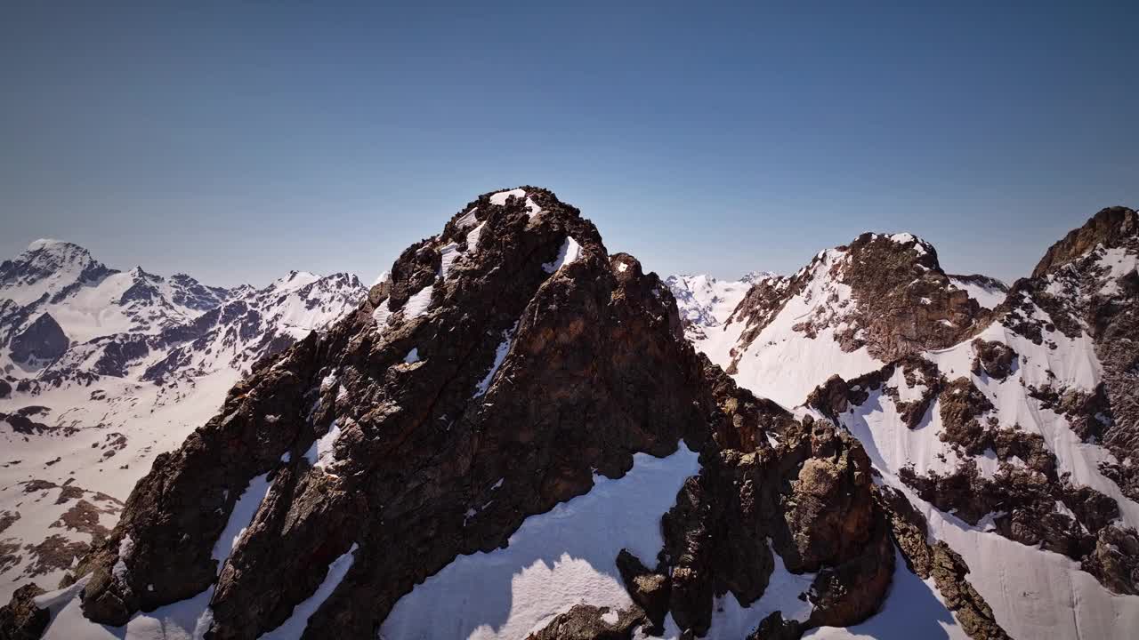 鸟瞰图在高高的雪峰周围飞行。用无人机拍摄的自然背景。视频下载