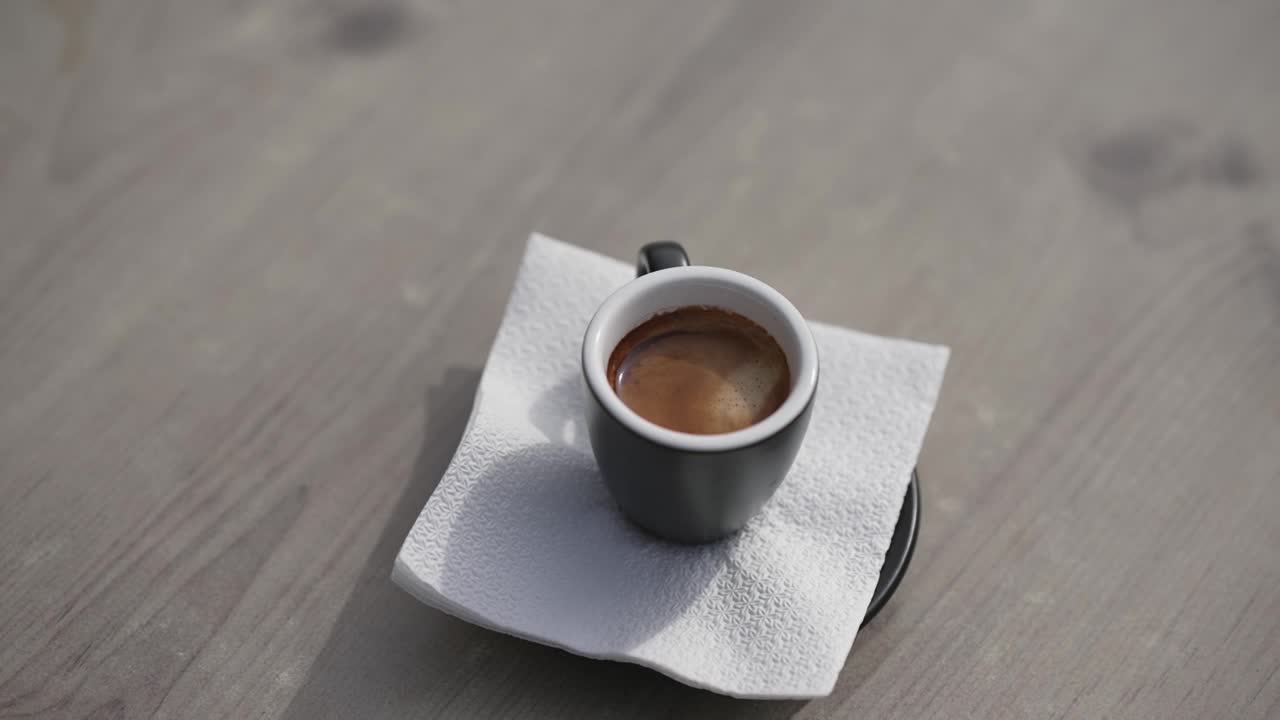 在咖啡馆吧台桌上的黑咖啡杯中倒入糖，选择性聚焦电影慢动作镜头视频下载