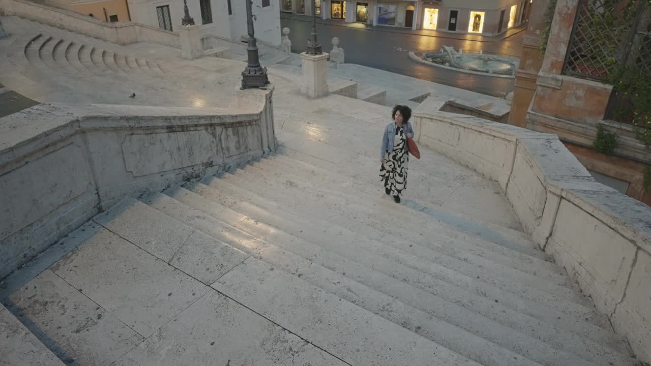 意大利罗马，一名身着意大利时尚风格的优雅女子在夜晚走在空旷的西班牙台阶上。意大利生活方式和旅行的概念，航拍视频下载