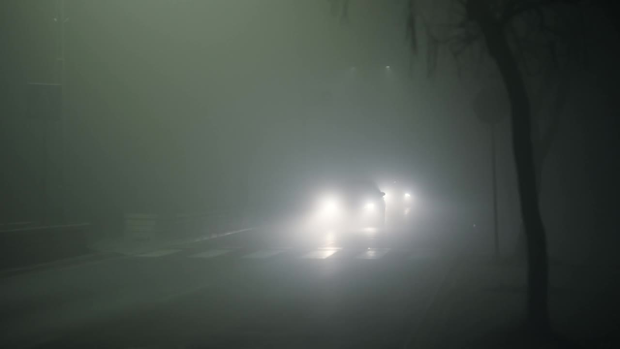 雾蒙蒙的夜晚道路上的交通被路灯照亮视频下载