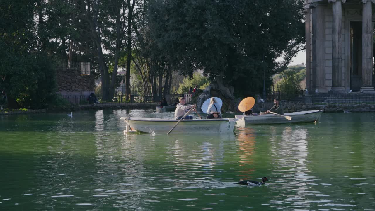 人们喜欢参观别墅Borghese划船与Tempio di Esculapio湖，Asklepios神庙背景在夏天阳光明媚的一天视频下载