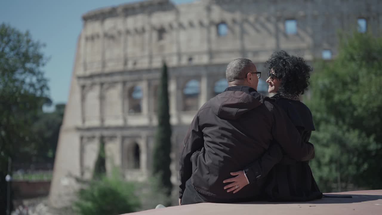 一对情侣坐在罗马斗兽场的公园观景台上接吻跳舞，意大利，选择性聚焦慢镜头视频下载