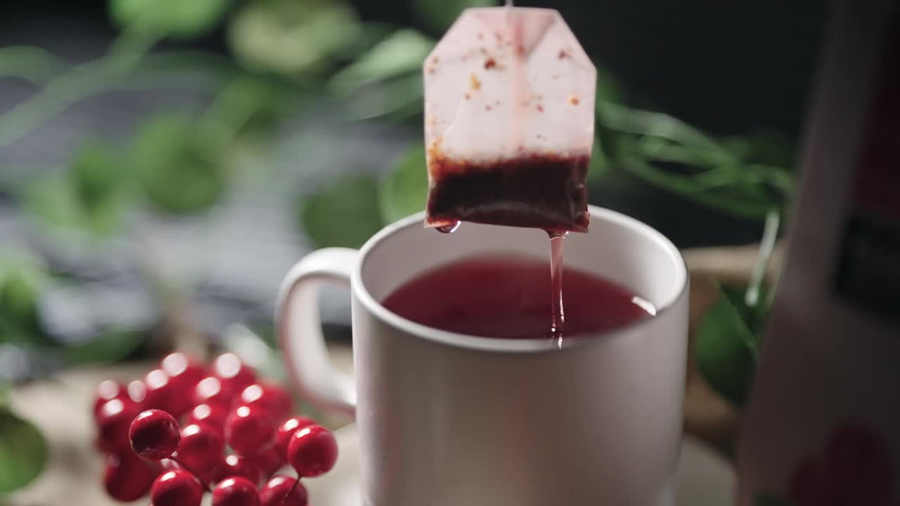 将蔓越莓茶包浸入杯中，电影般孤立的慢动作镜头视频下载