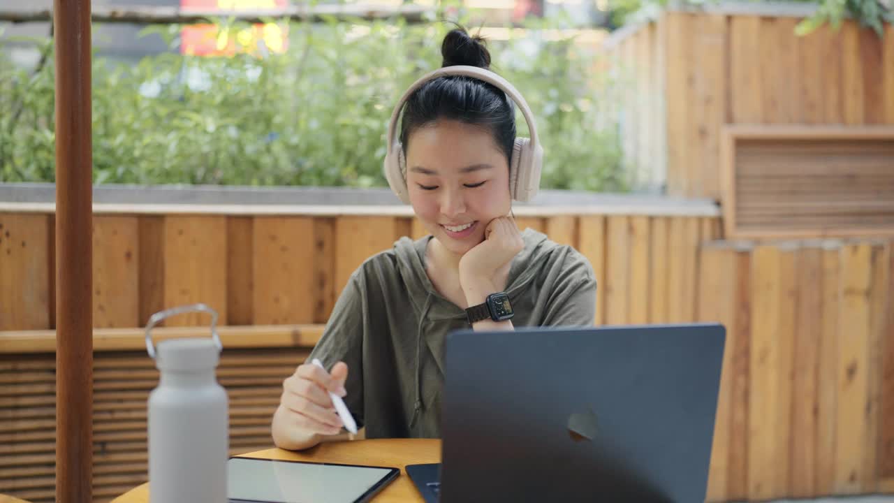 一名年轻女子使用笔记本电脑独自进行在线学习。视频下载