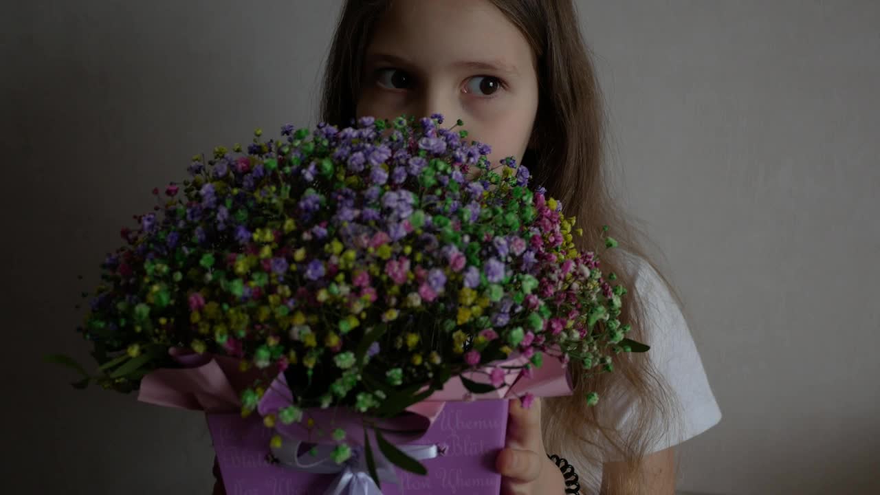 一个可爱的小女孩的肖像，带着一束创意的彩色花束。春天到了，母亲节快乐。视频下载