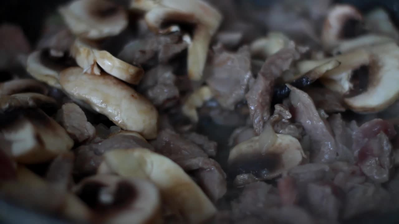 香菇和肉在煎锅里煎(特写)。做一道传统的肉菜视频下载