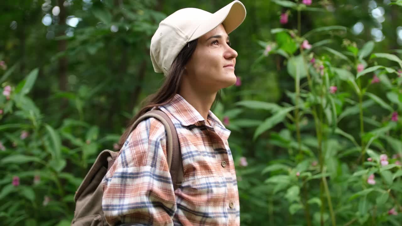 徒步旅行的女人走在森林里。夏天的一天，徒步旅行的女孩背着背包穿过森林视频下载