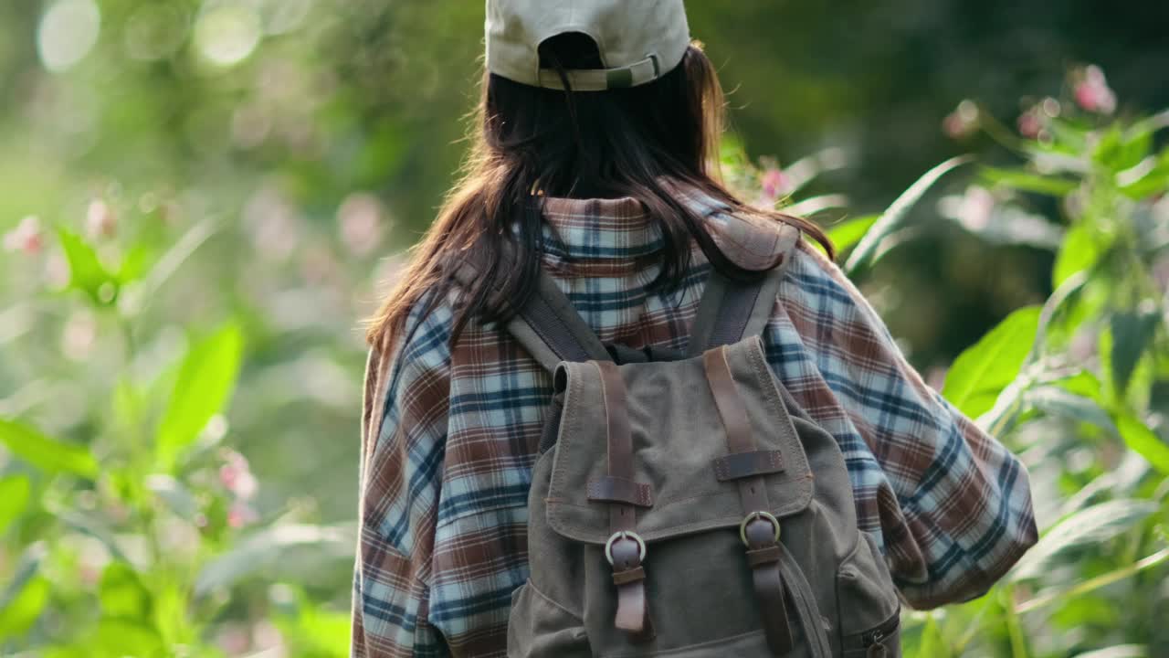 徒步旅行的女人走在森林里。夏天的一天，徒步旅行的女孩背着背包穿过森林视频下载