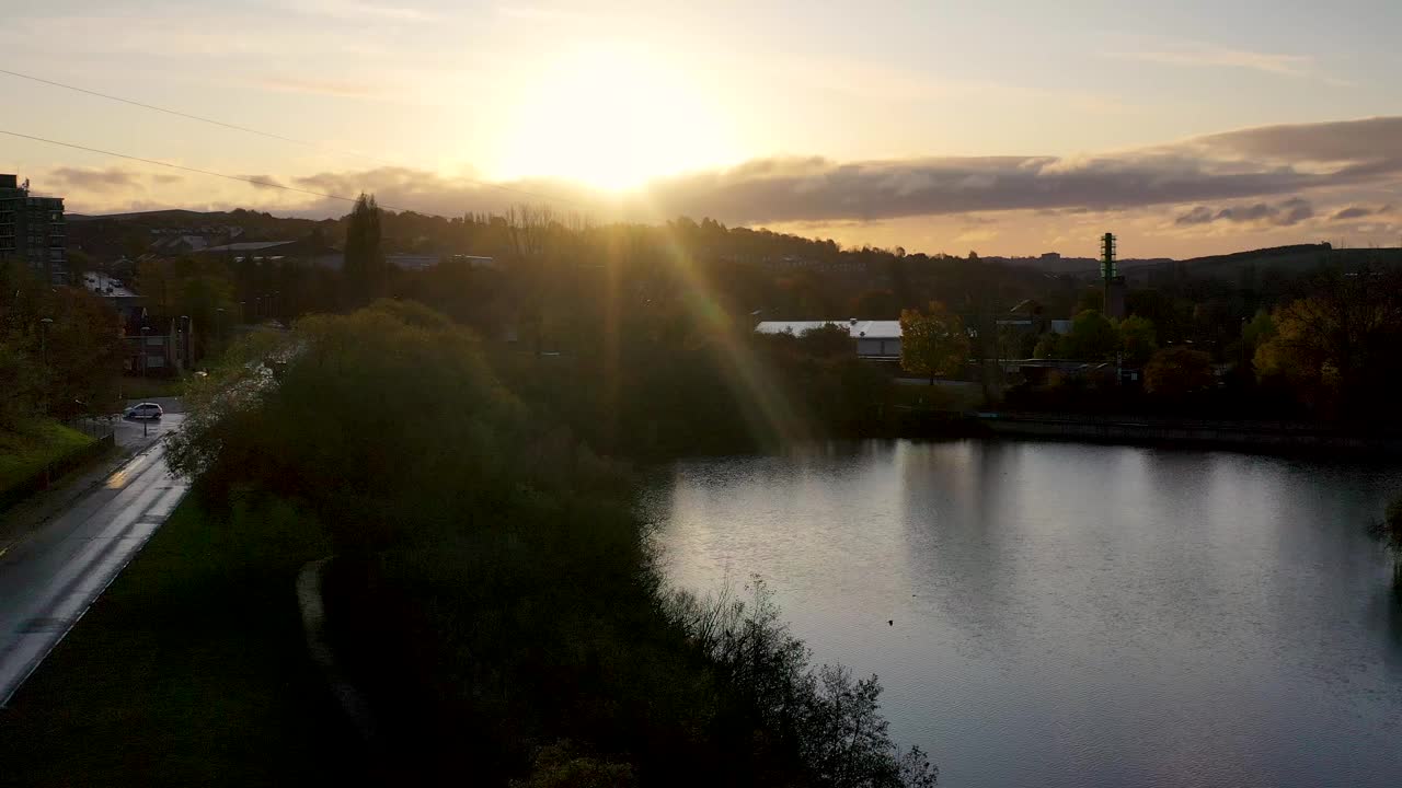 这是英国西约克郡利兹一个名为法恩利的村庄的航拍画面，背景是日出的住宅区和一个大池塘视频下载