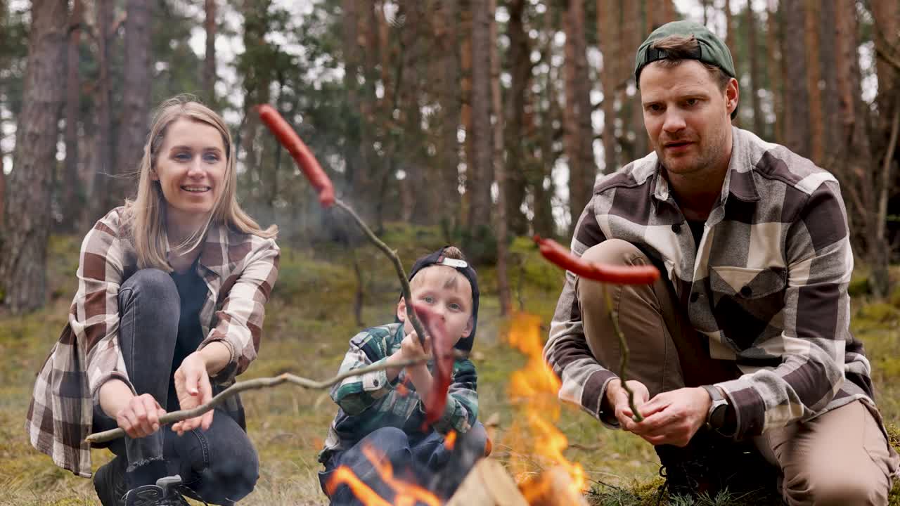 一家人在森林里的篝火上煎香肠。自然野餐、露营视频下载