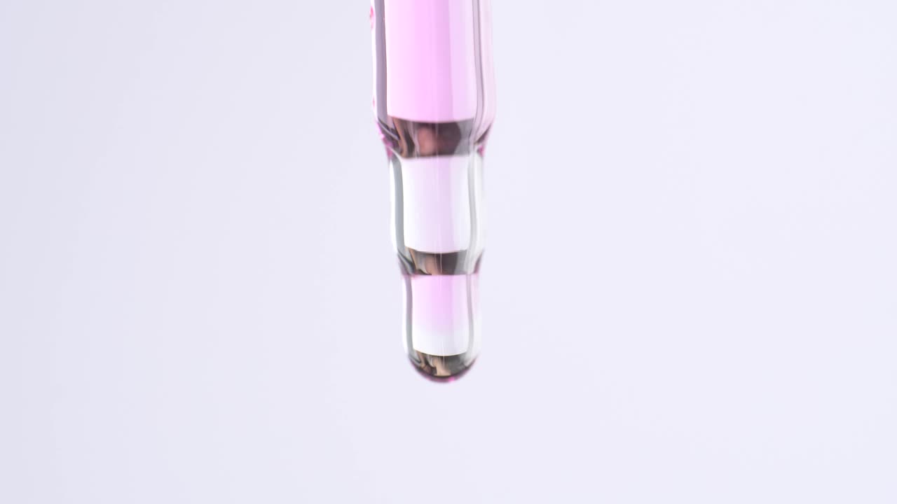 近距离的移液器与粉红色的角质层油。从玻璃移液管中滴下精油或血清。视频下载
