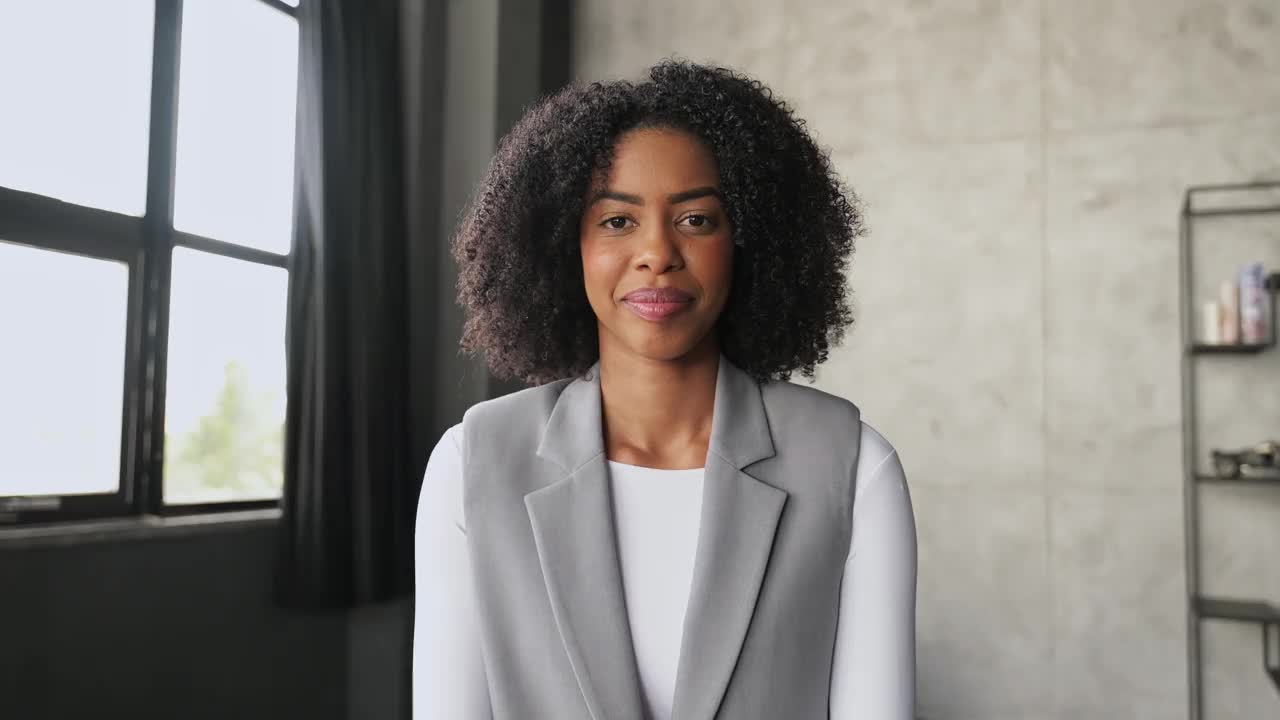 在视频通话中，一位非洲裔美国妇女带着灿烂的微笑和挥手向她的同事打招呼视频下载