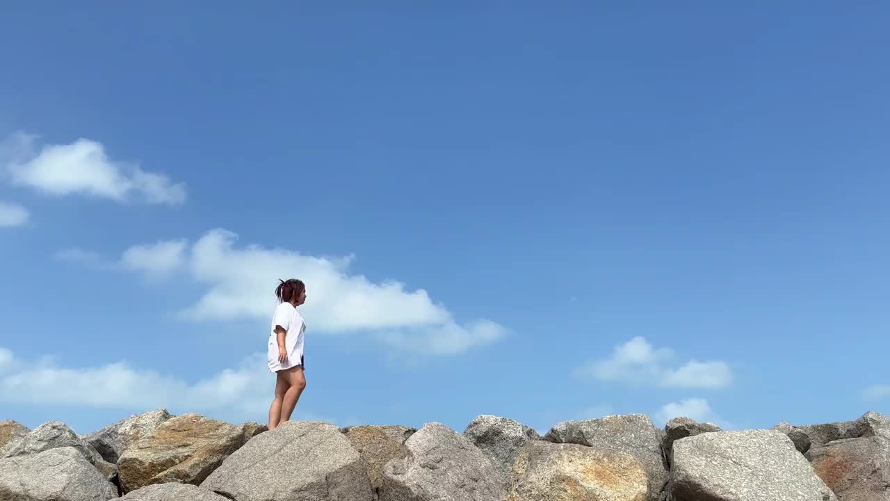 一名女子站在大堤上，用智能手机对着蓝天拍照视频下载