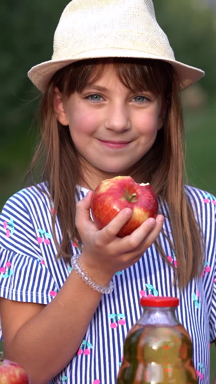 可爱的小蓝眼睛女孩在阳光果园吃红苹果视频下载
