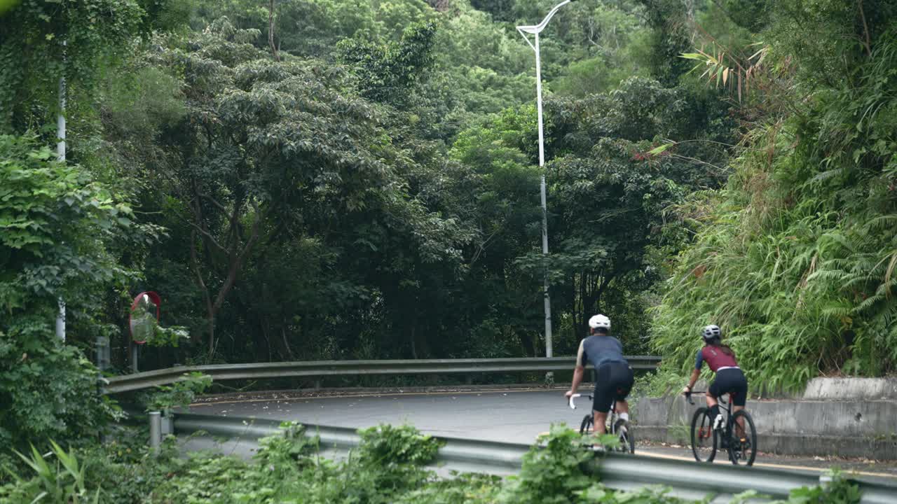 年轻的亚洲夫妇在乡村公路上骑自行车视频下载