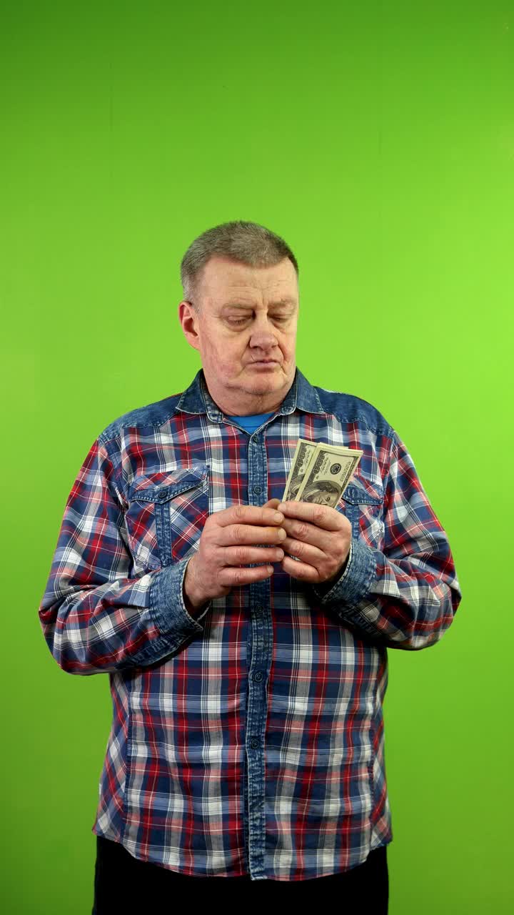 穿着便服的老人满意地数着钱，把钱放进口袋。视频下载