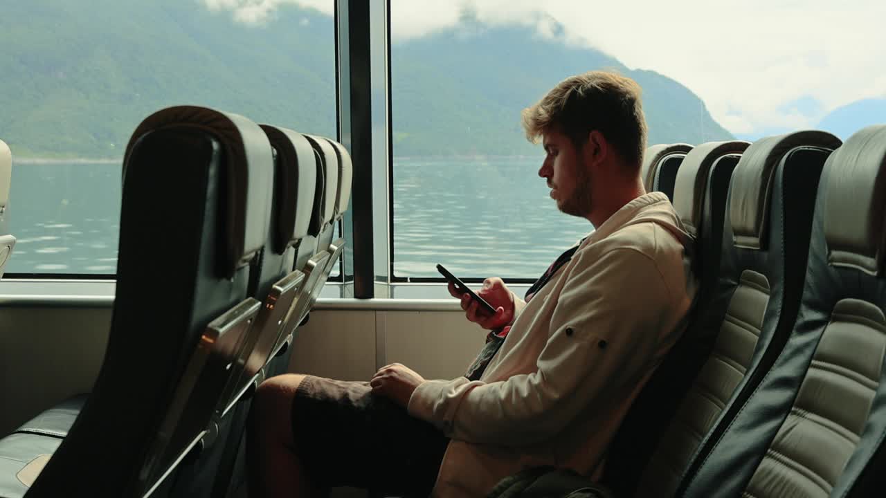 男子用智能手机与山景一起乘船渡海视频下载