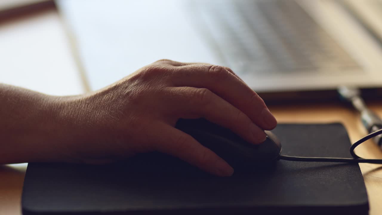 在家庭办公室用鼠标在笔记本电脑上工作的女性，使用输入设备的女性双手特写视频下载