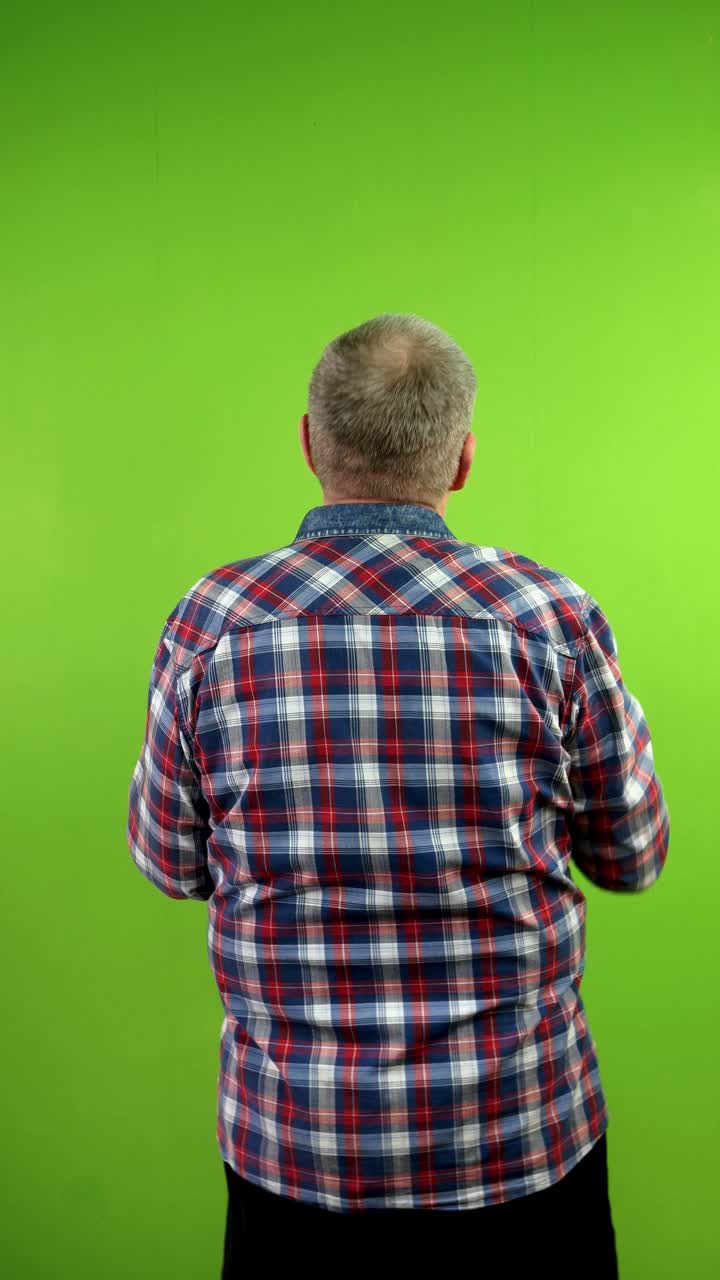 老人在绿色墙壁上触摸、滑动、滑动的后视图。视频下载