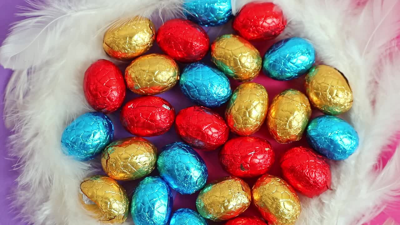 巧克力复活节彩蛋从购物车里洒出来，背景是淡紫色。视频下载