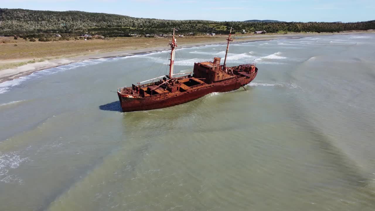海浪拍打着一艘锈迹斑斑的沉船，它躺在巴塔哥尼亚海岸灰色的浅水里视频下载