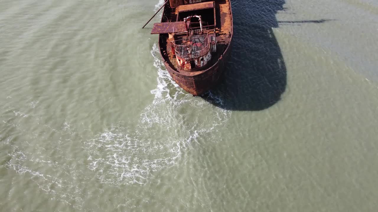 镜头沿着巴塔哥尼亚海岸浅水区一艘锈迹斑斑的沉船往上平移视频下载