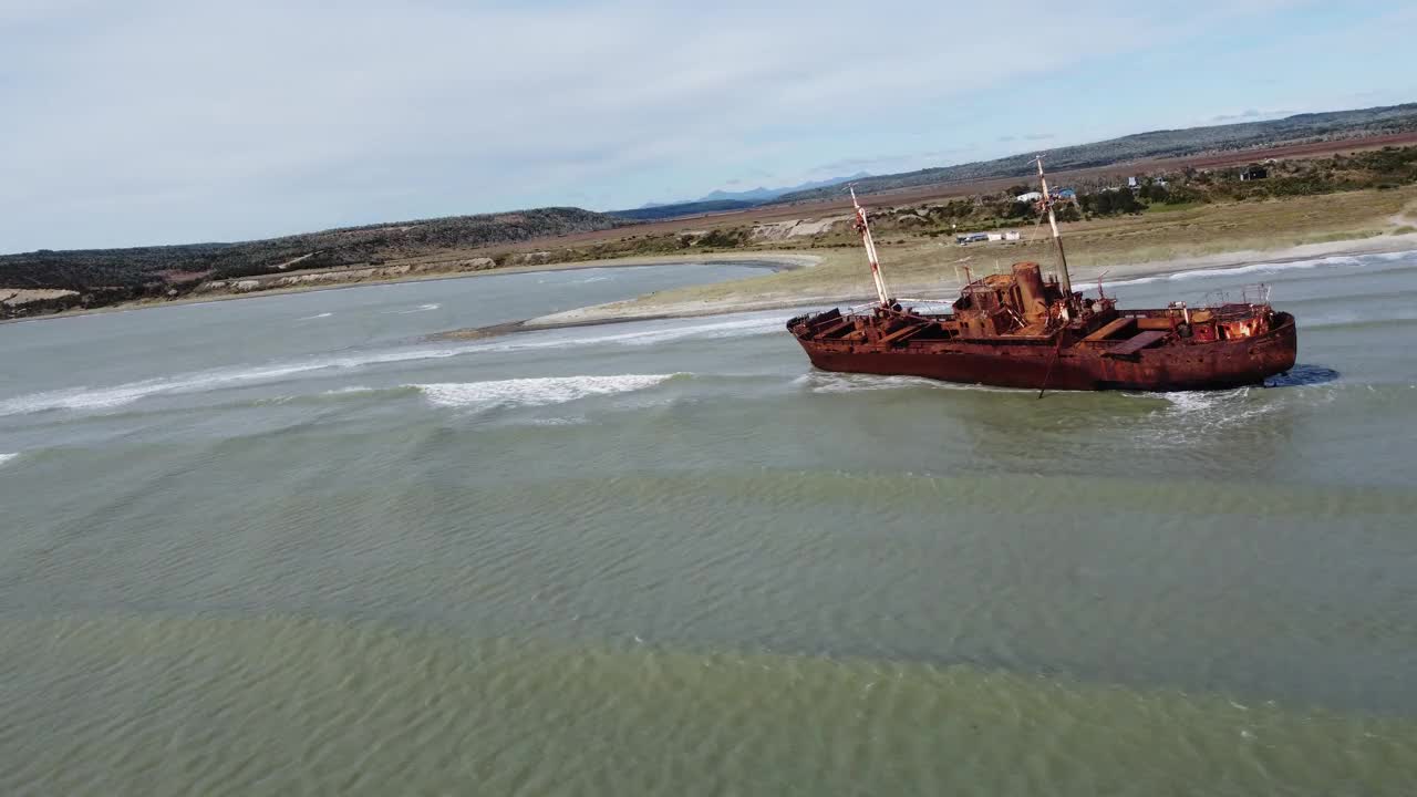 镜头经过巴塔哥尼亚海岸浅水区一艘锈迹斑斑的沉船视频下载