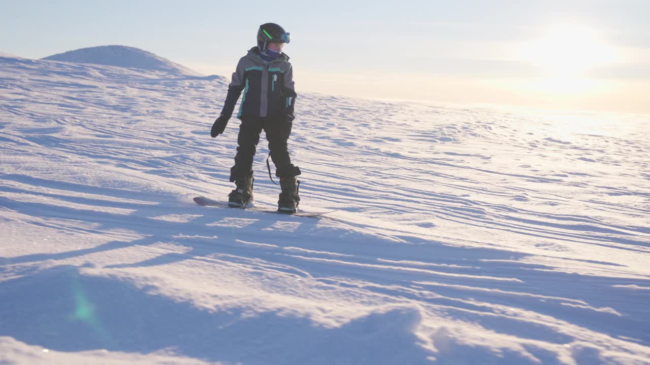 一个男孩在阳光明媚的雪景中单板滑雪视频下载