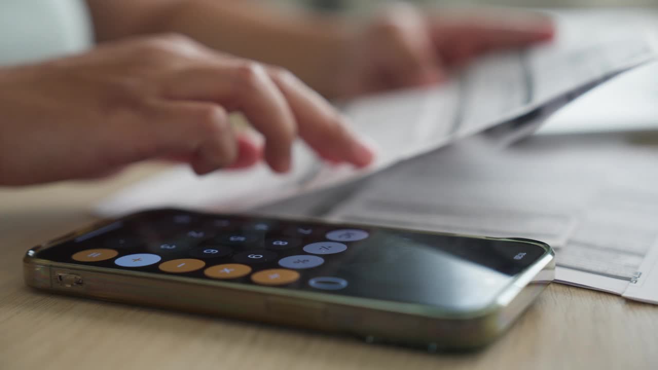 女人手里拿着一个手机计算器，计算着家里的财务开支、账单视频下载