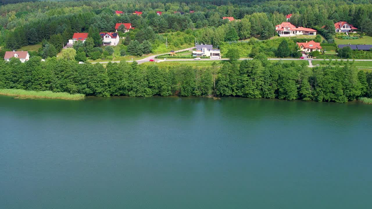 美丽的湖，岸边有房子。池塘宁静祥和。壮丽的鸟瞰平静的湖泊与岛屿在波兰。天堂湖岸边的乡村房屋。水面上的宁静。视频下载