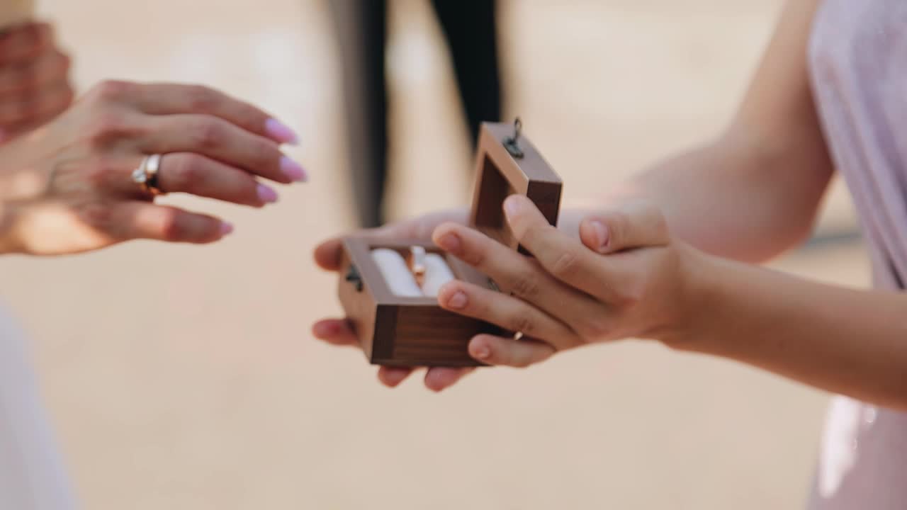 一个女孩从首饰盒里拿出一枚订婚戒指，戴在她男人的手上。视频下载