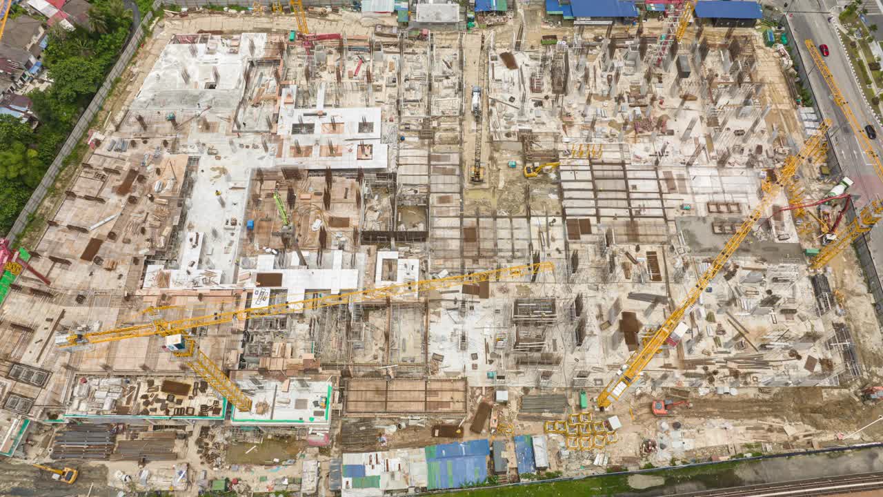 白天飞行在城市中心工作的建筑场地空中俯视全景4k延时马来西亚视频下载