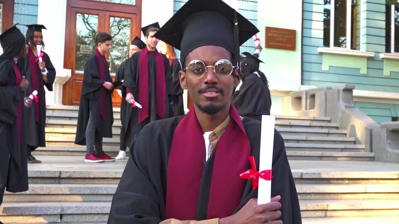 一位男学者拿着毕业证书站在那里视频素材