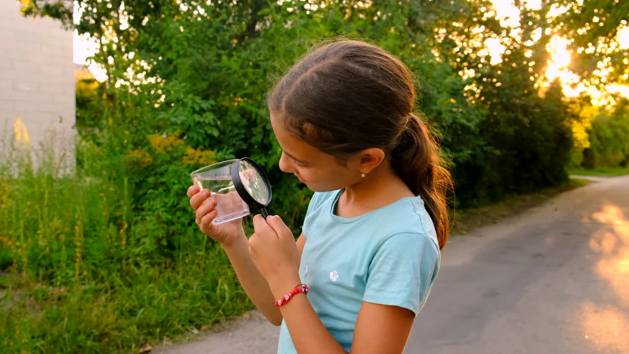 一个孩子用放大镜看一杯水。有选择性的重点。孩子。视频下载