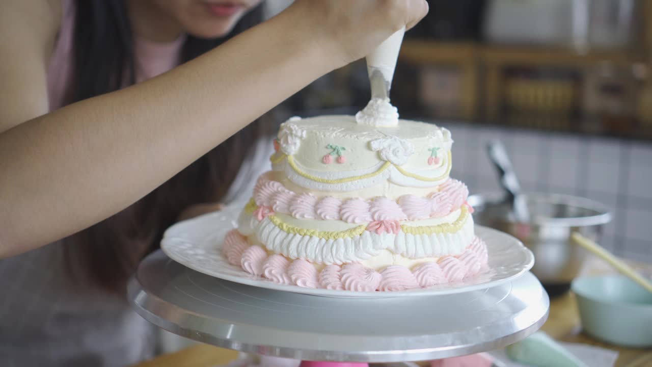 面包店里的女人用鲜奶油装饰蛋糕。视频下载