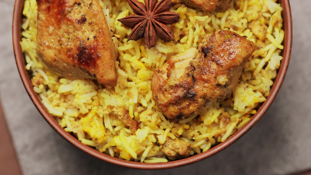 在粘土碗里用香料和柠檬做的鸡肉比亚尼饭，流行的印度和巴基斯坦食物，倾斜相机运动视频下载