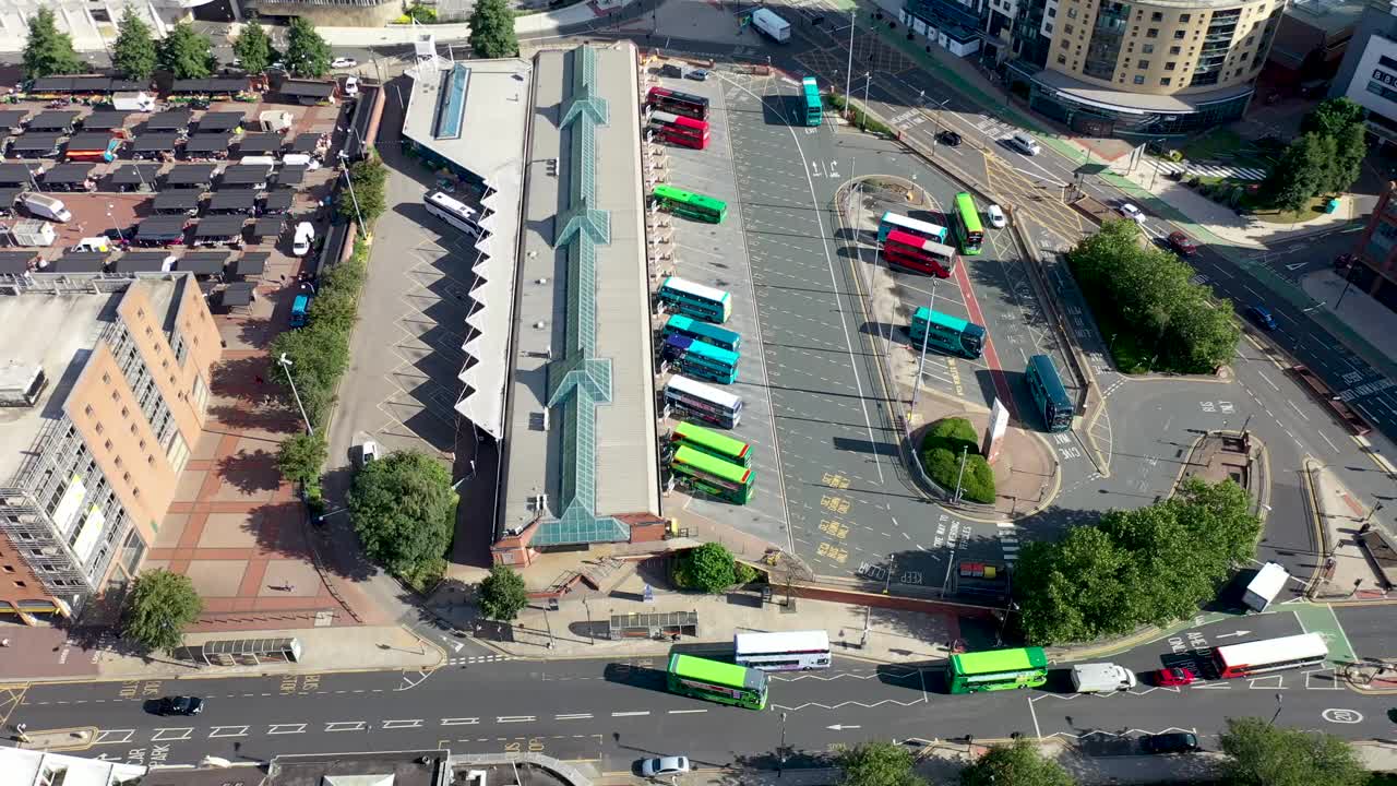 在一个炎热晴朗的夏日里，利兹市中心的航拍画面显示，无人机在公交车站上空盘旋，公交车在公交车站上下车视频下载