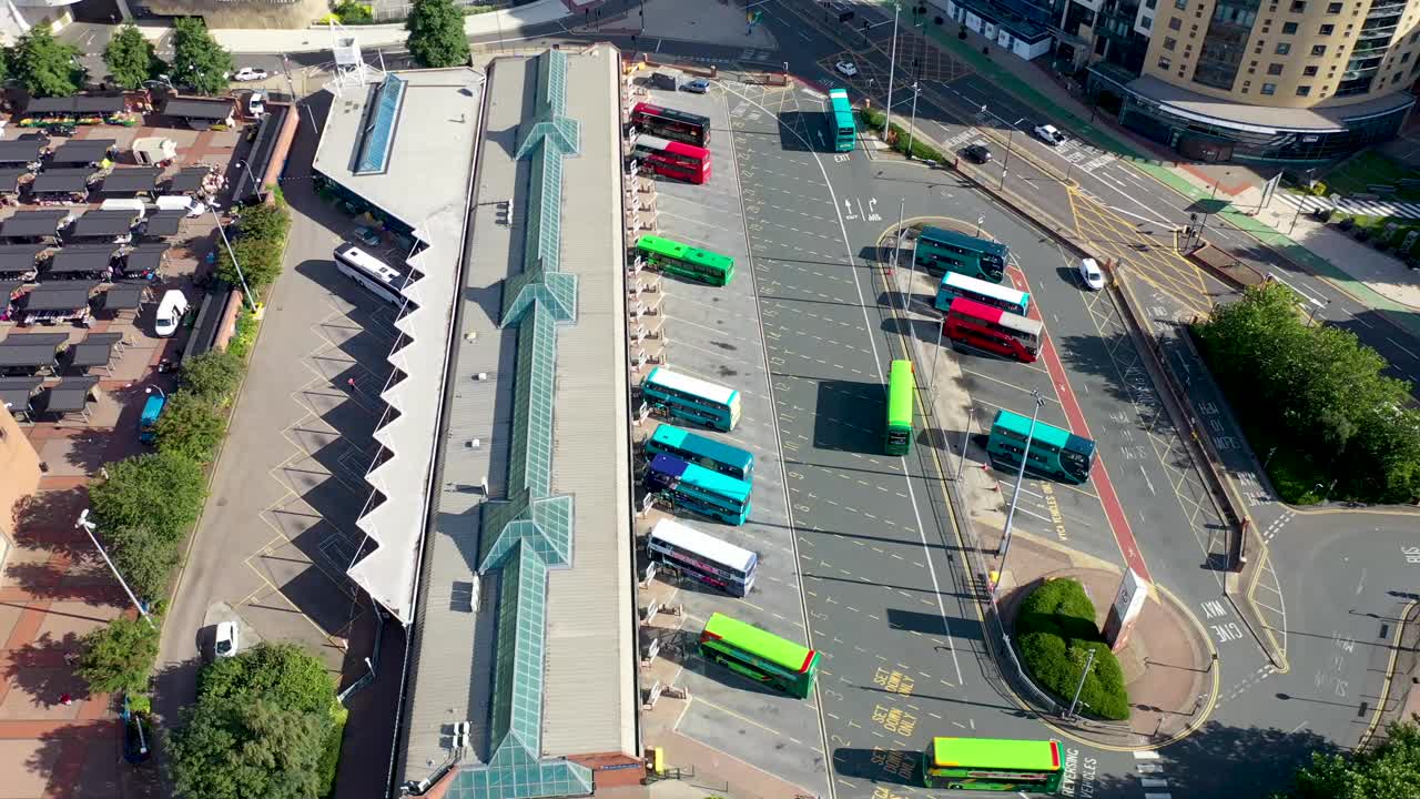 在一个炎热晴朗的夏日里，利兹市中心的航拍画面显示，无人机在公交车站上空盘旋，公交车在公交车站上下车视频下载