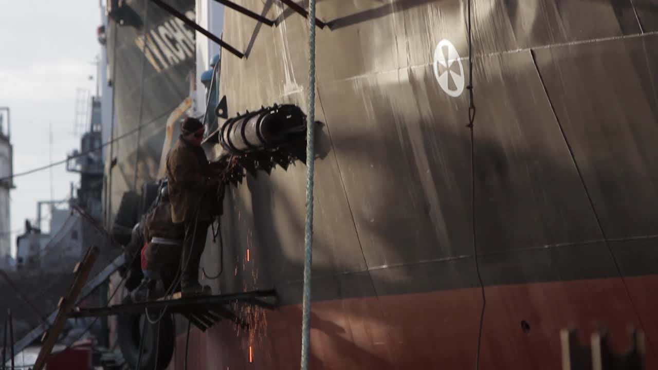 由焊工在浮船坞进行船舶修理工作。穿着防护装备的工人在船体上使用焊接设备，火花飞溅。船舶工业维修、检修在船厂捕获。视频下载