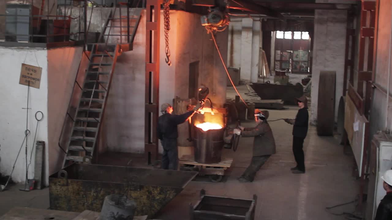工业铸造工人倒熔金属，团队炼钢，重工业工人操作高温，极端工作环境下佩戴防护装备，精密金属铸造。视频下载