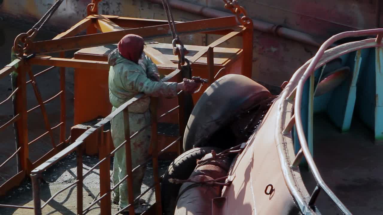 穿着防护装备的工人在浮船坞给船体涂漆。工业船舶维修，船体涂装工艺进行中。船厂工人在船舶表面喷涂防护涂料视频下载