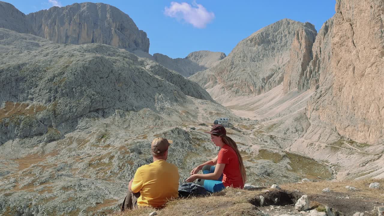 女人和男人徒步旅行者放松与壮观的山脉在高姿态视频下载