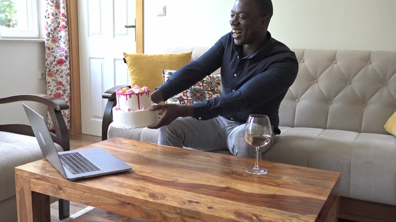 一名男子正在用笔记本电脑视频通话，向朋友展示他的生日蛋糕视频下载