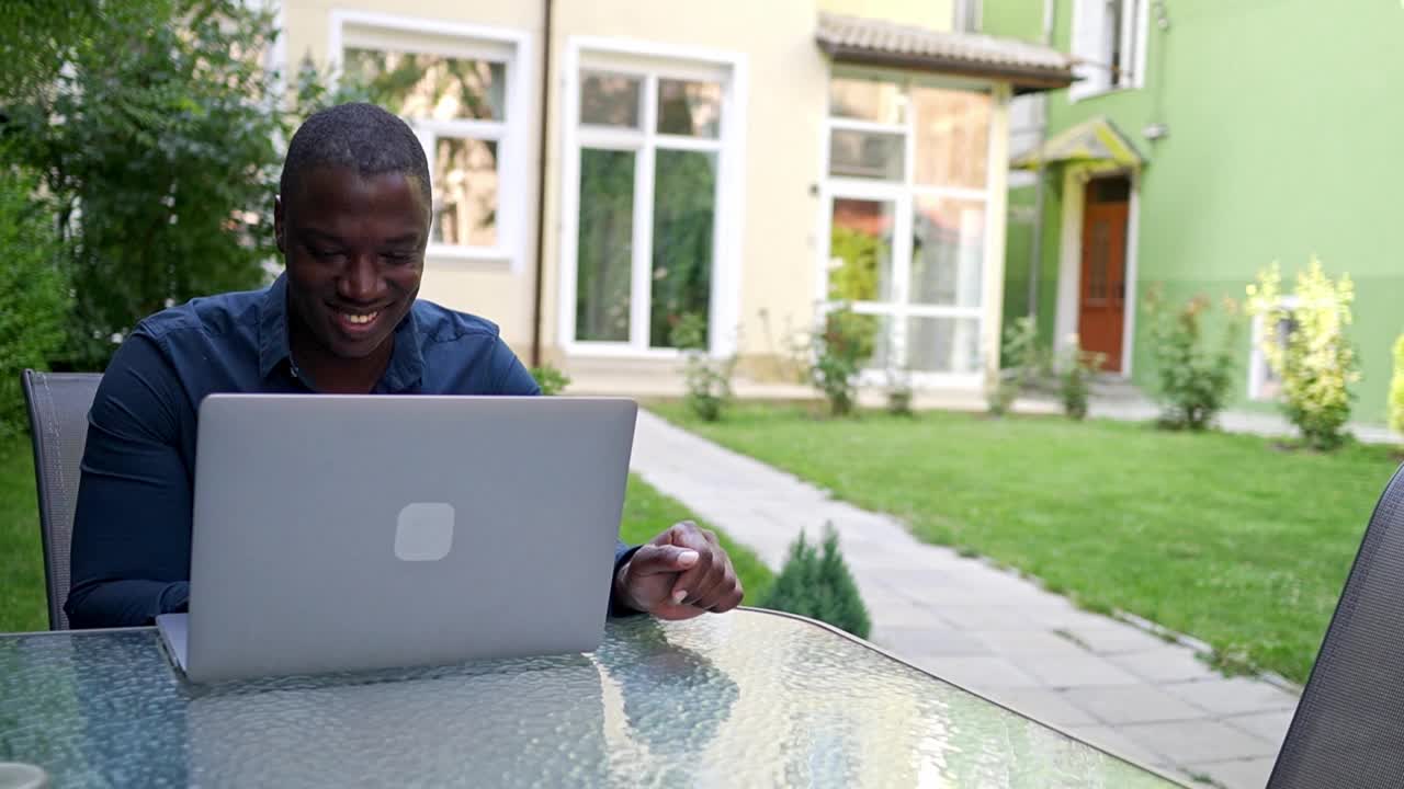 在家办公，一位面带微笑的男士放下笔记本电脑休息了一下视频下载