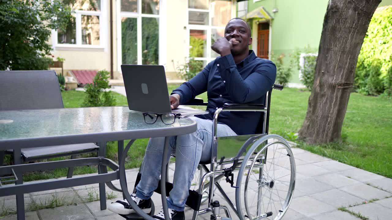 一个正在康复的人，坐在轮椅上用笔记本电脑在花园里工作视频素材