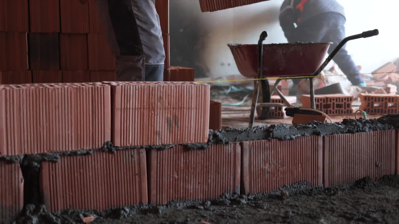 特写砌砖:工地上的建筑工人视频下载