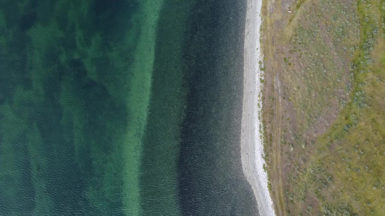 摄像机沿着比格尔海峡的海岸移动，绿色的大海和小波浪白色的卵石滩视频下载
